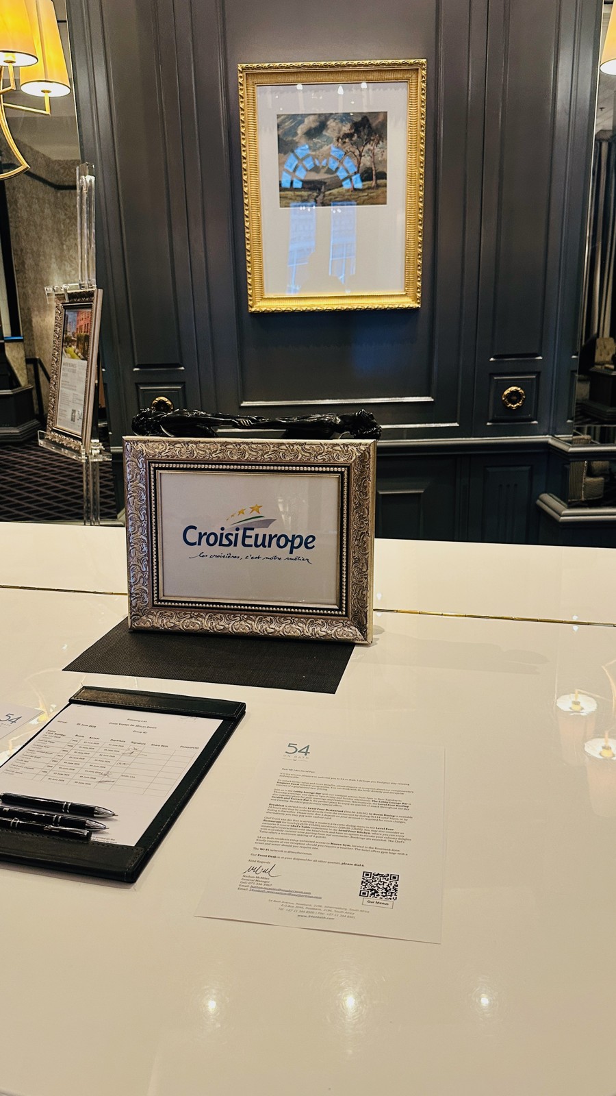 The CroisiEurope welcome desk at the 54 on Bath hotel in Johannesburg, with a framed CroisiEurope logo and the group welcome letter